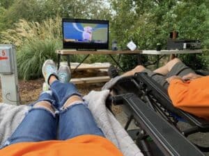 Two people sitting in a lawn chair watching tv.