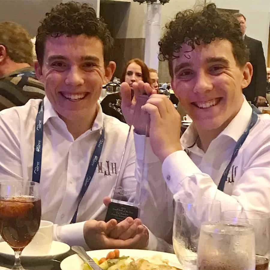 Two young men holding awards at a banquet.